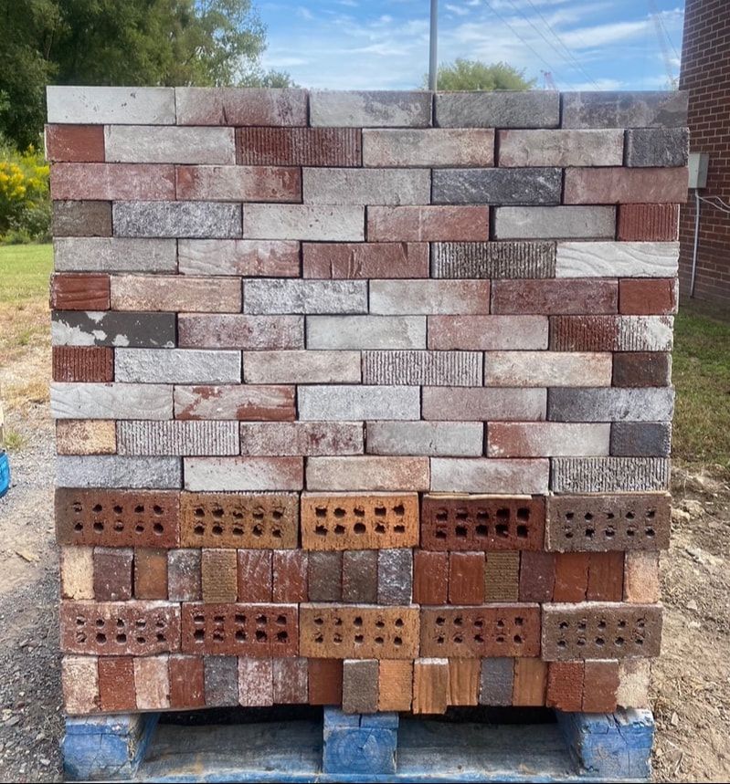 Stack of multicolored bricks on a wooden pallet outdoors, for construction or building.