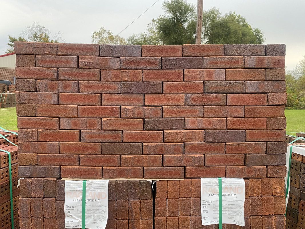 Stack of red and brown bricks, outdoors, ready for construction.