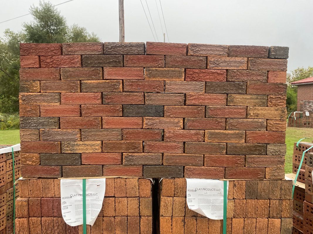 Stack of red and brown bricks, outdoors.
