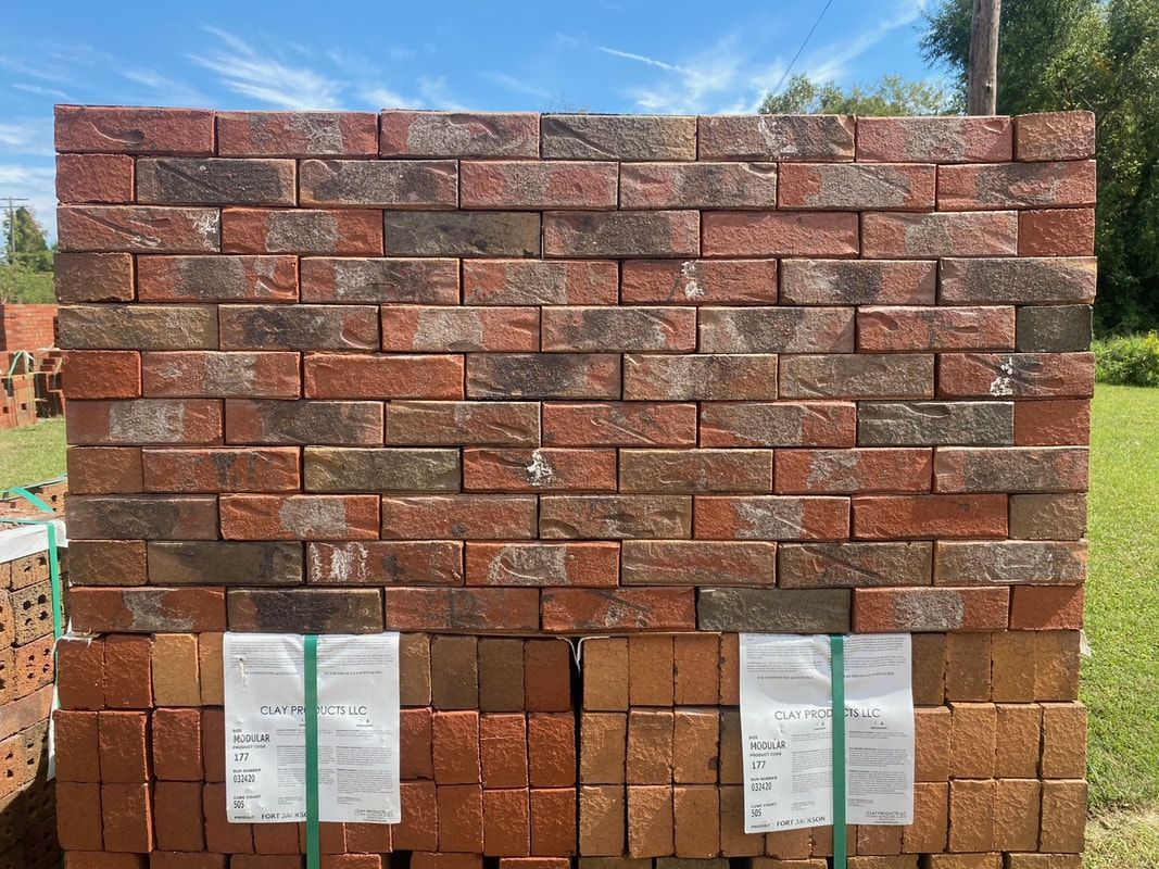 Stacked red and brown bricks, likely for construction, outdoors on a sunny day.