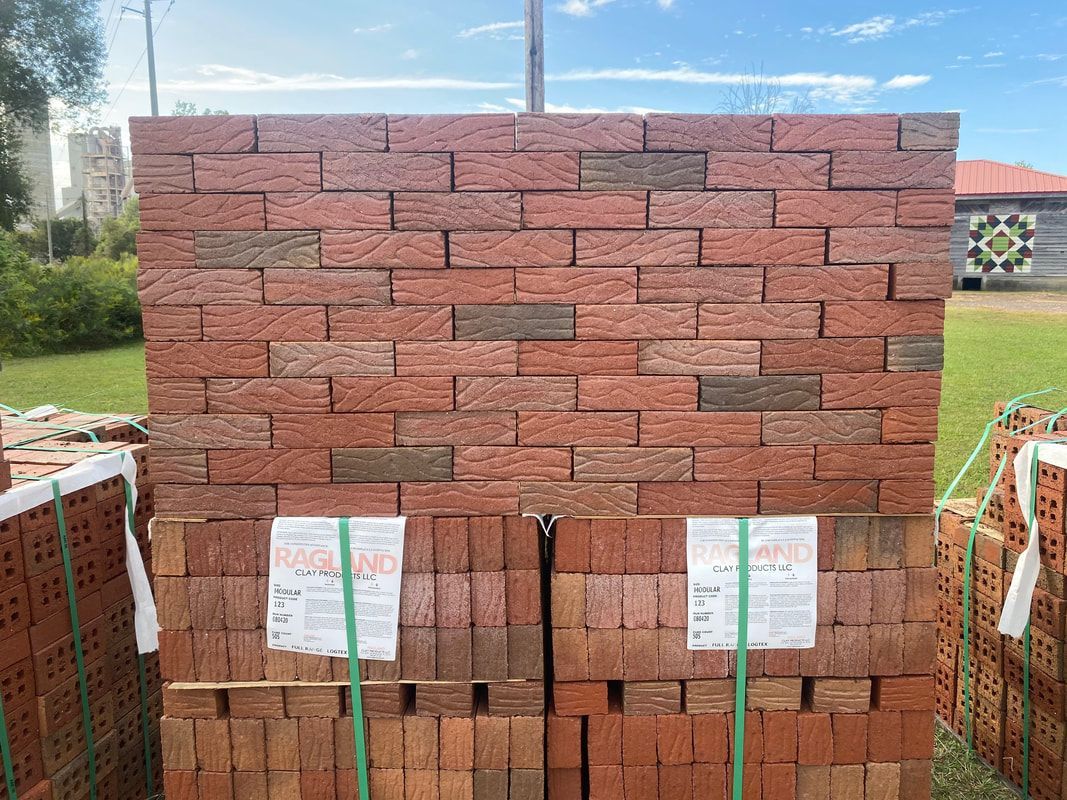 Stack of red bricks, outdoors, ready for construction.