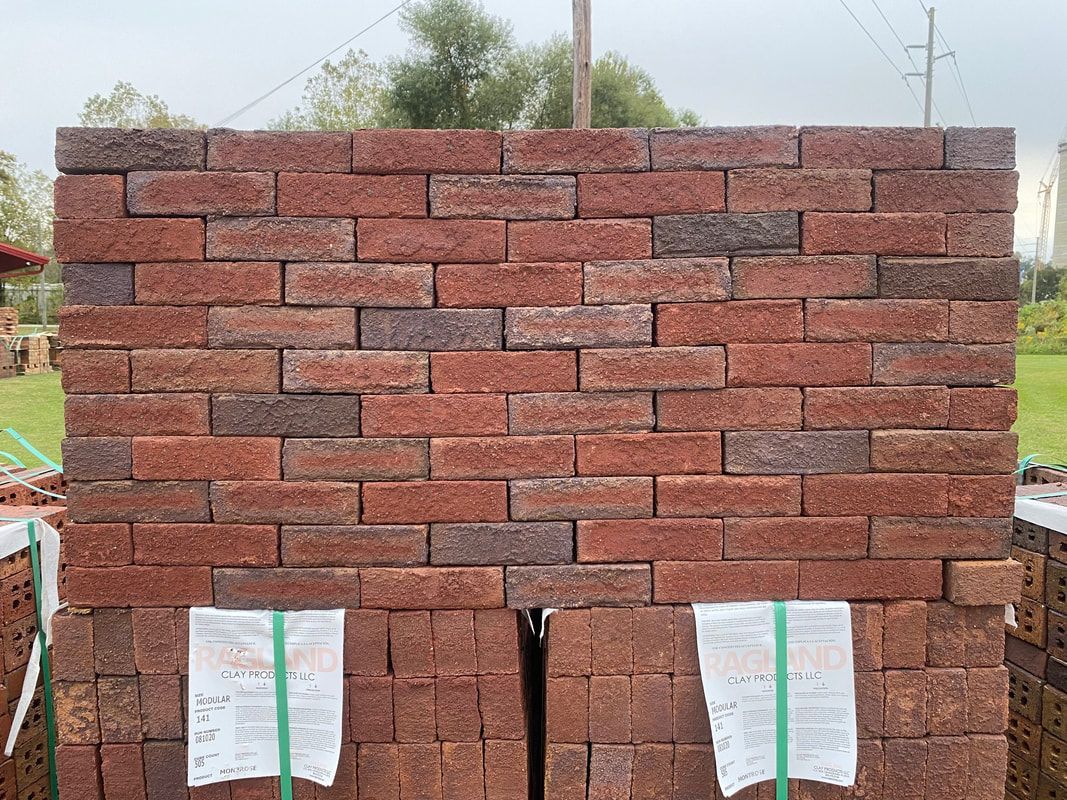 Stack of red and brown bricks, outdoors.