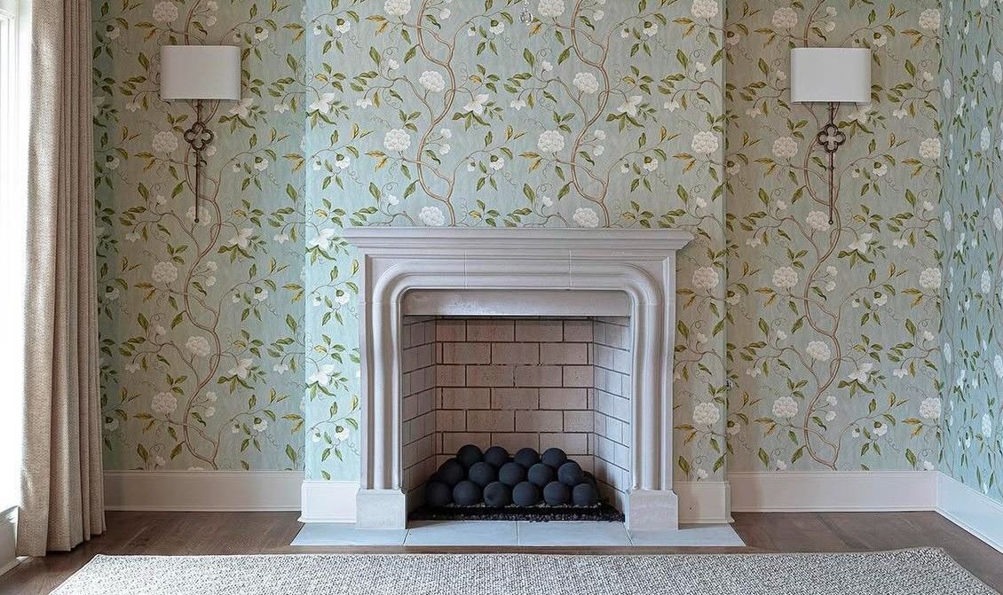 Fireplace with floral wallpaper and sconces.