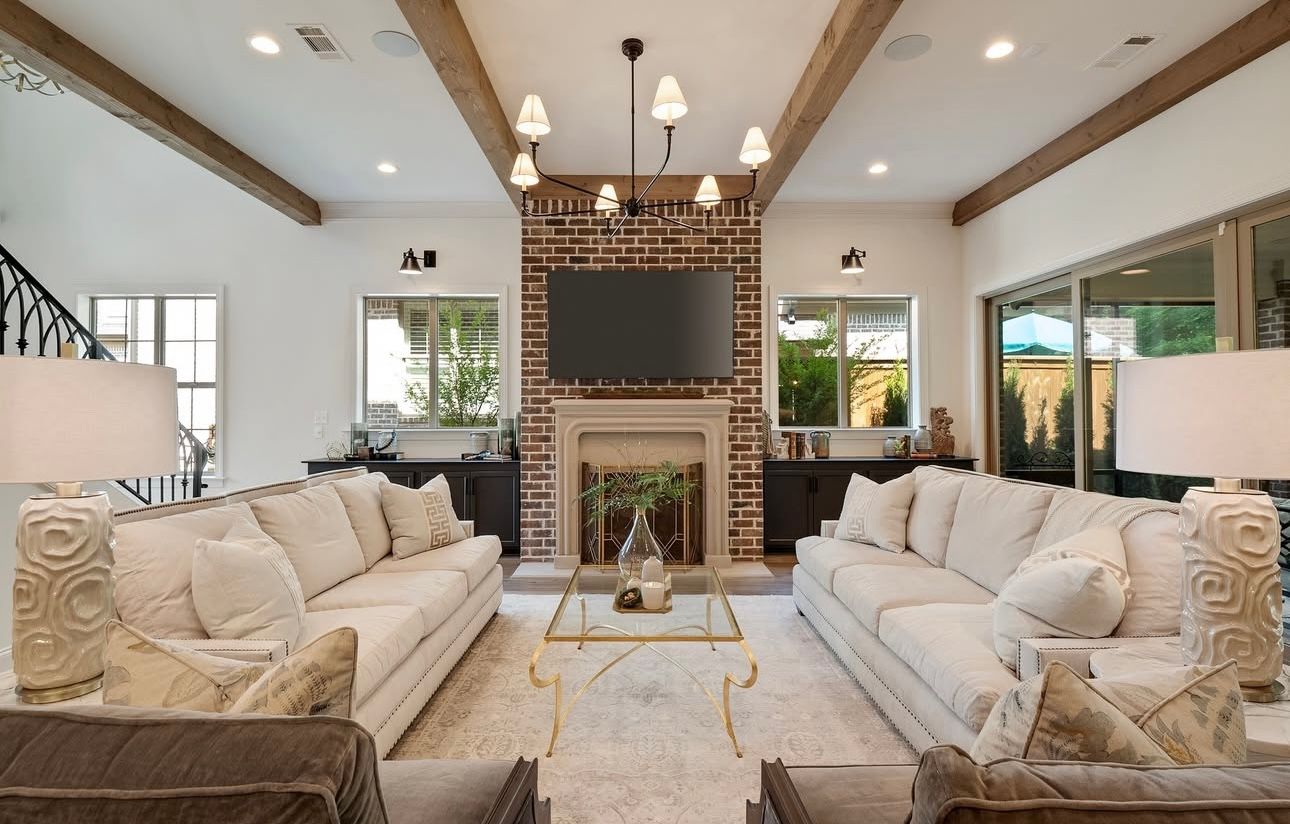Living room with white sofas, brick fireplace, and exposed wood beams.