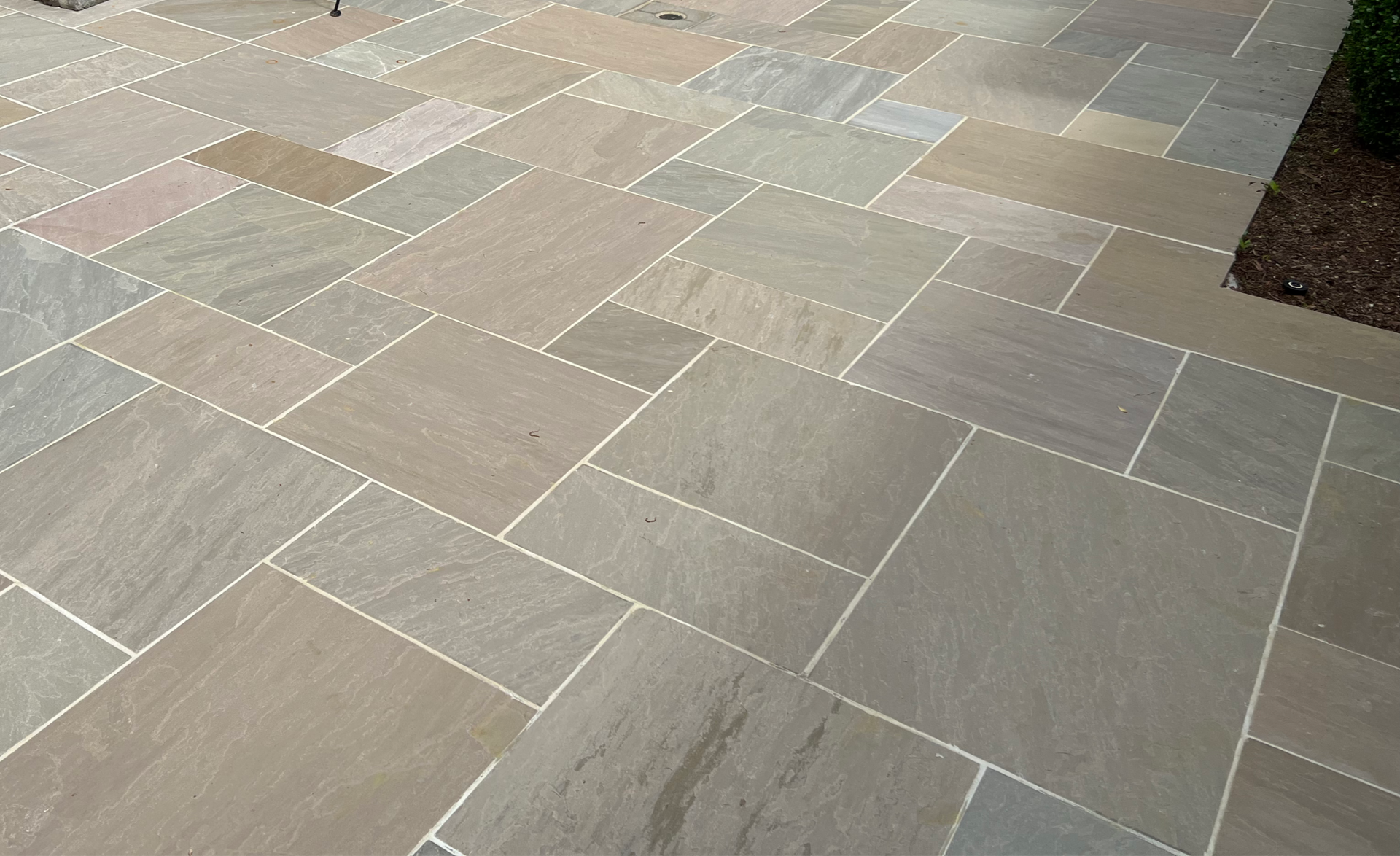 Tan stone patio with light-colored grout.