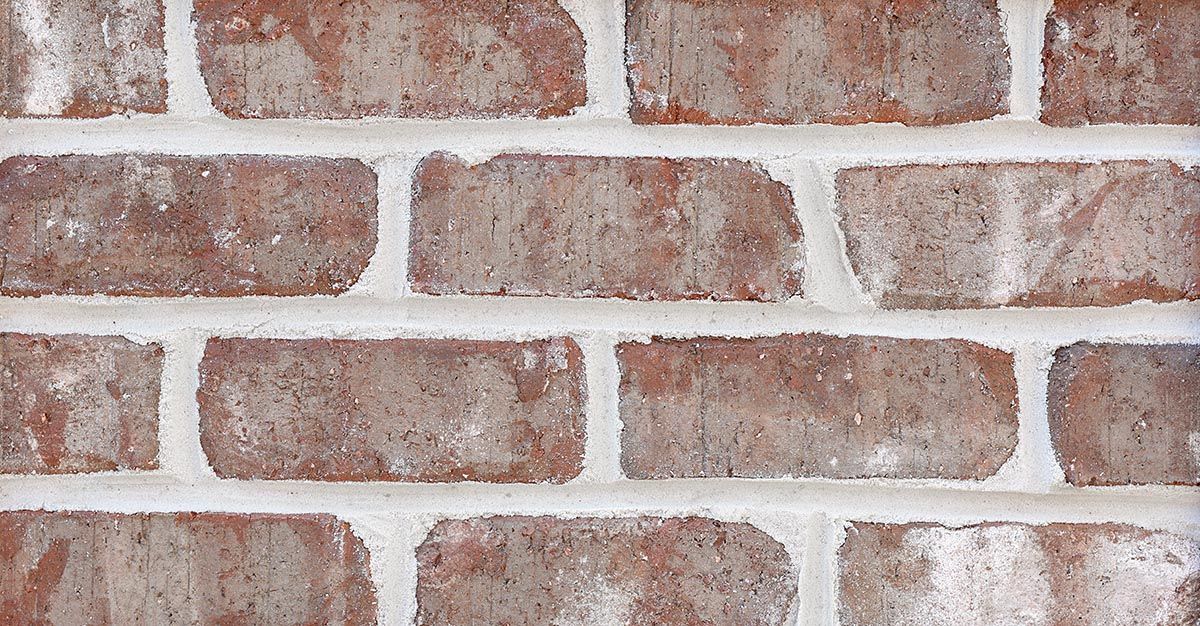 Close-up of red and brown brick wall with white mortar.