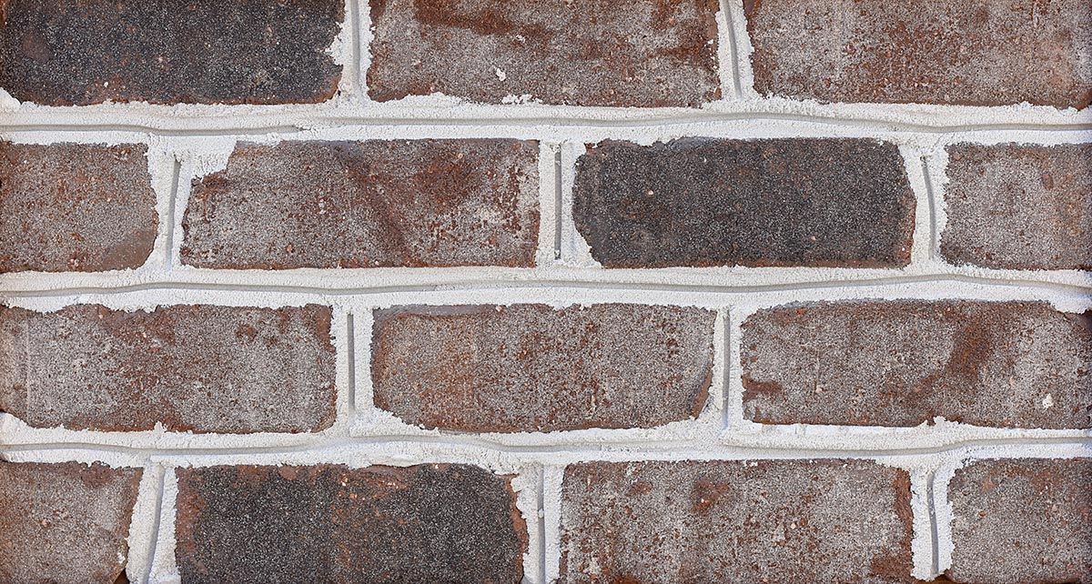 Close-up view of a brick wall with gray and brown bricks and white mortar.