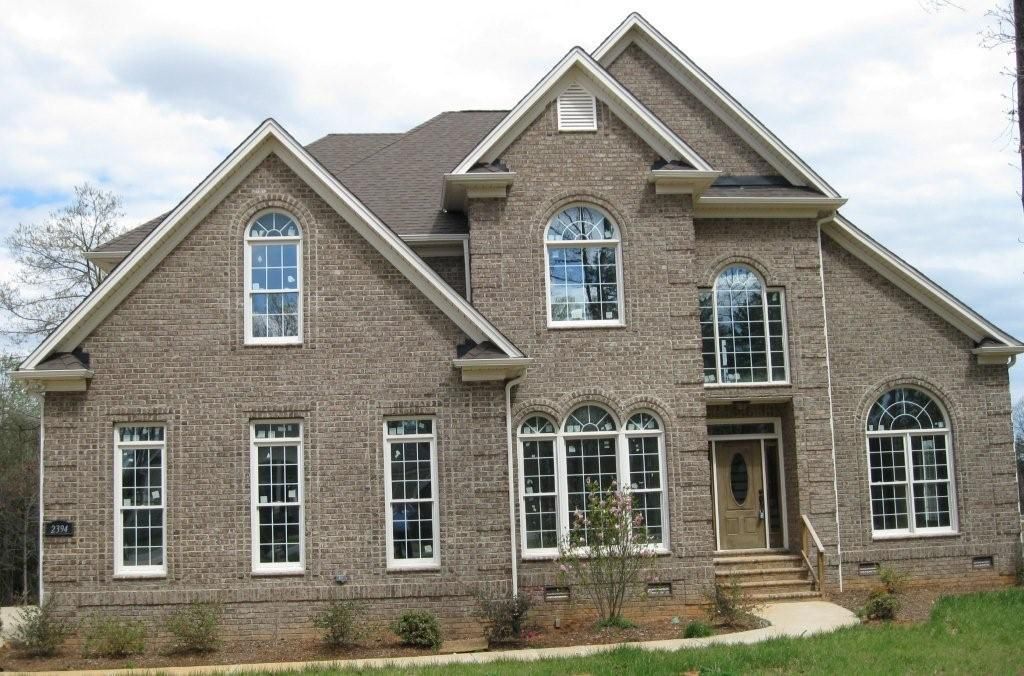 Two-story brick house with white trim, arched windows, and a brown roof.