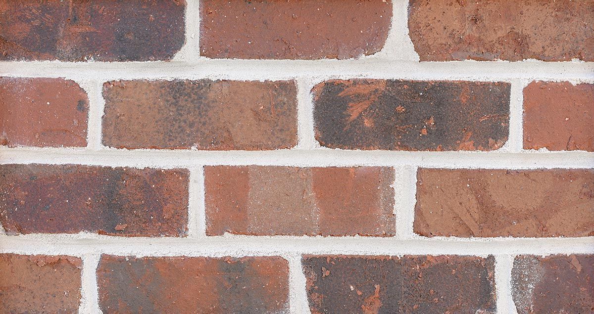 Close-up of a brick wall with red and brown bricks separated by white mortar.