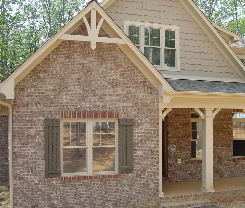 Brick house with beige trim, tan siding, and a covered porch.