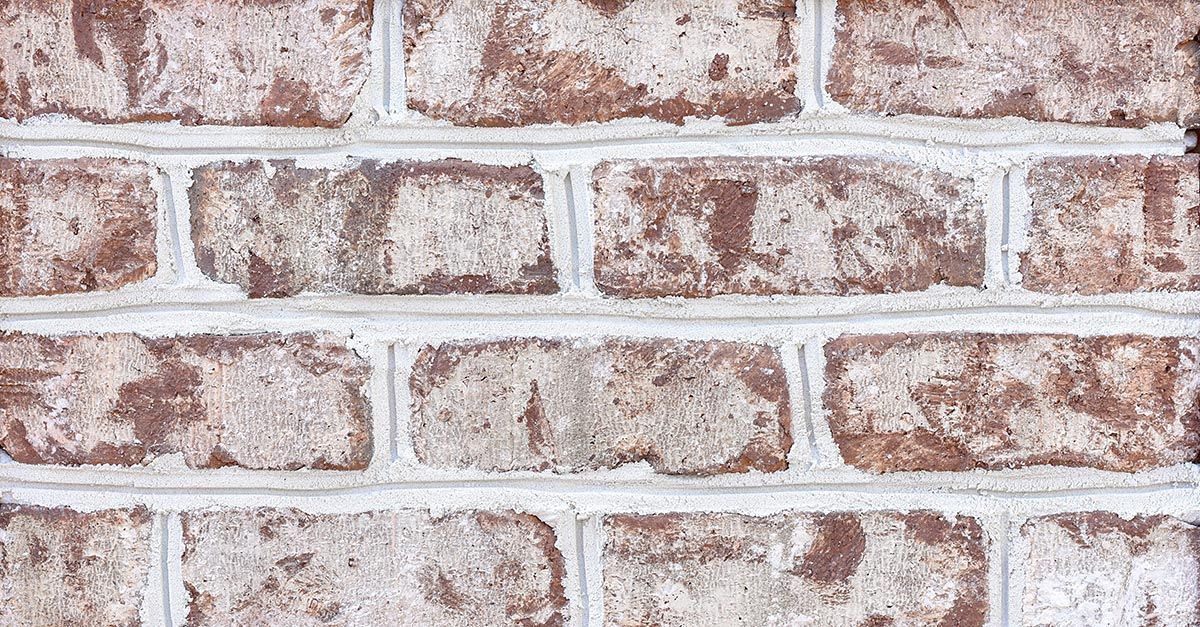 Brick wall with light mortar. Red-brown bricks with mottled texture.