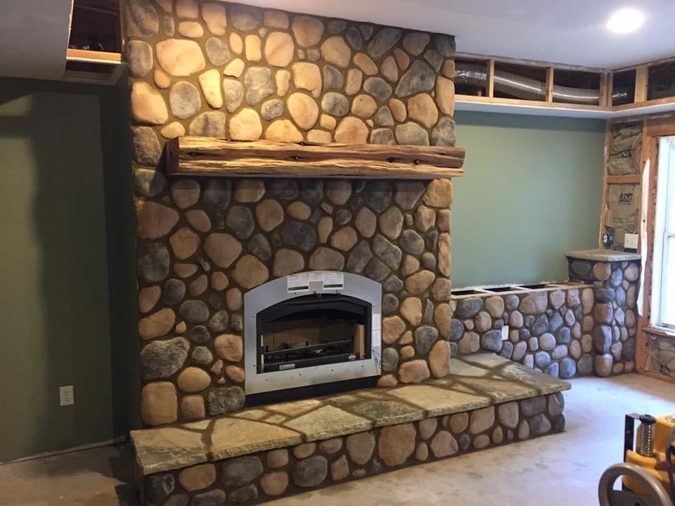 Stone fireplace with wooden mantle and hearth.