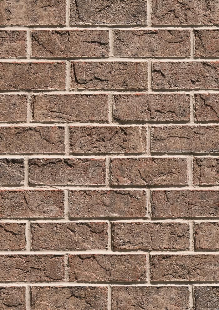 Brown brick wall with light-colored mortar between the bricks.