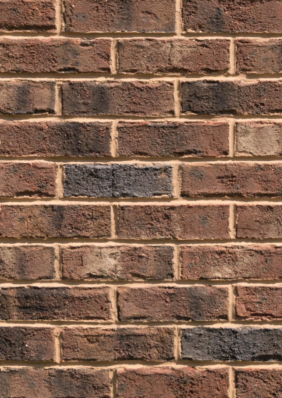 Brown brick wall with light-colored mortar between bricks.