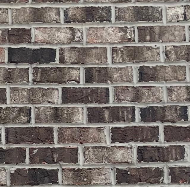 Close-up view of a brick wall, featuring varying shades of brown, gray, and white mortar.