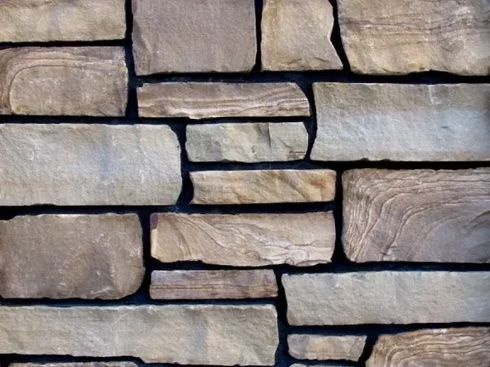 Stone wall, beige and brown rectangular stones, dark grout.
