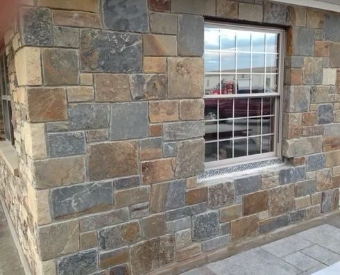 Exterior stone facade with a window, in tones of brown, gray, and tan.