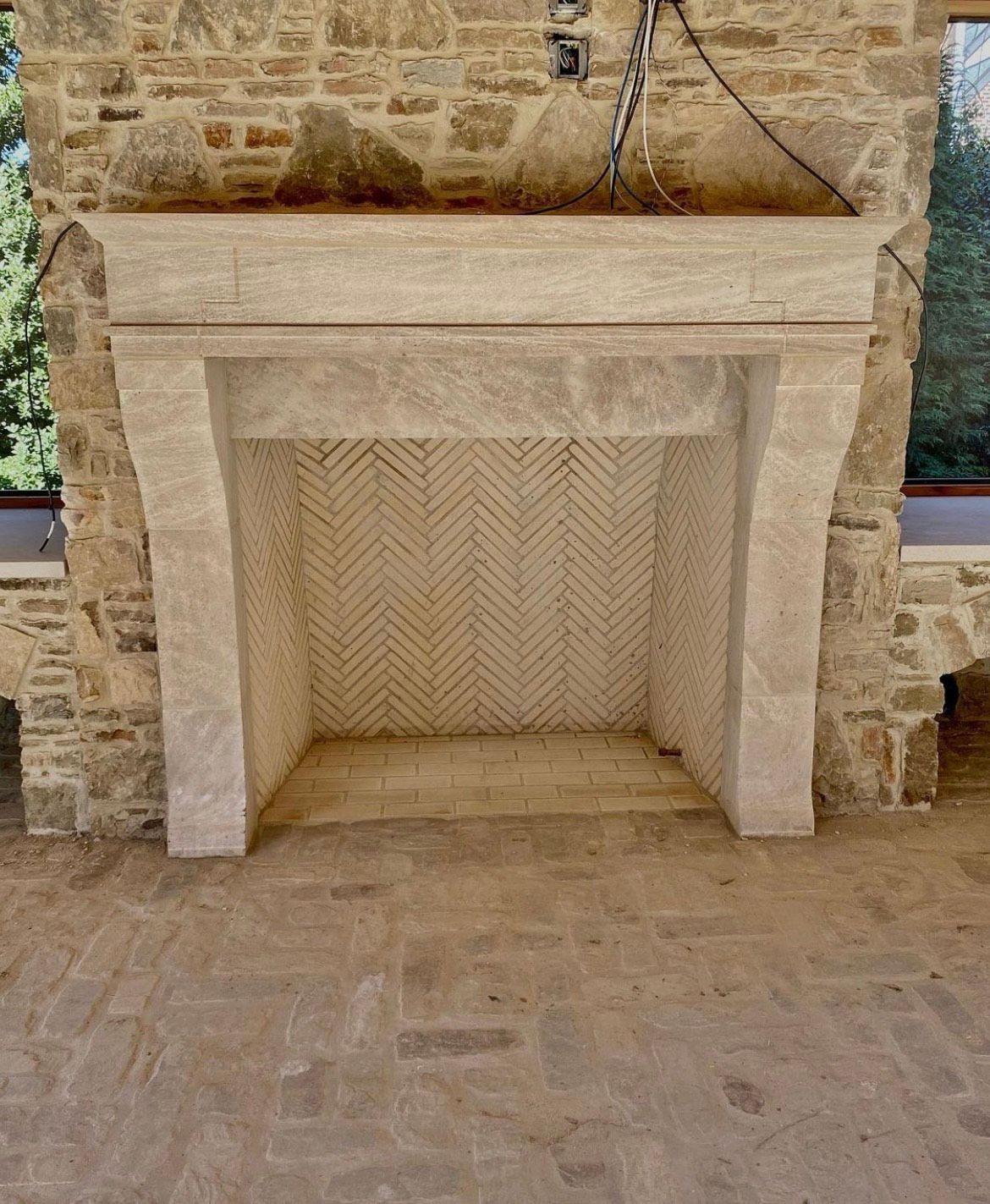Stone fireplace with herringbone brick interior, set against a stone wall.