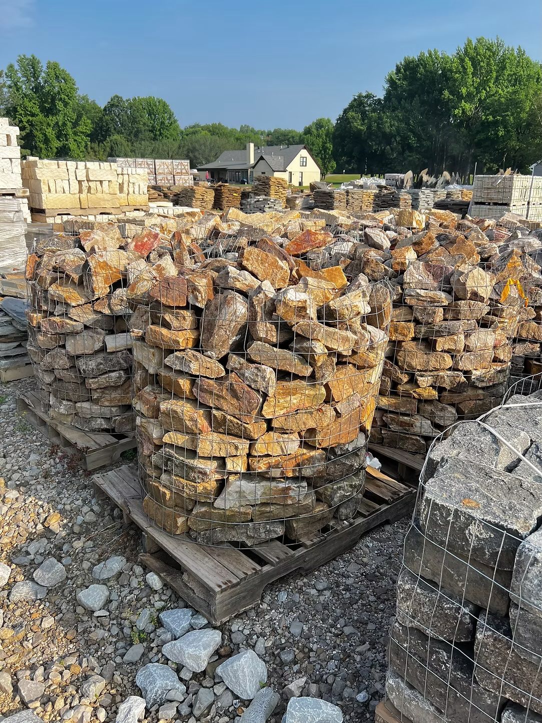 Bundles of tan and brown rocks on pallets, outdoors.