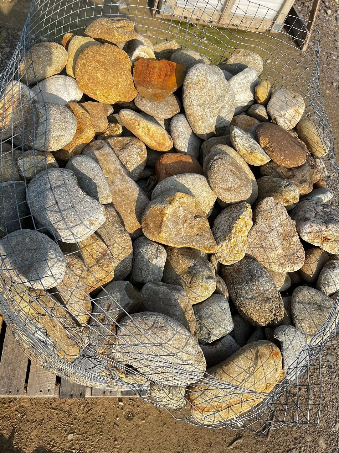 Rocks in a wire mesh cage, varying shades of brown and gray, outdoors.