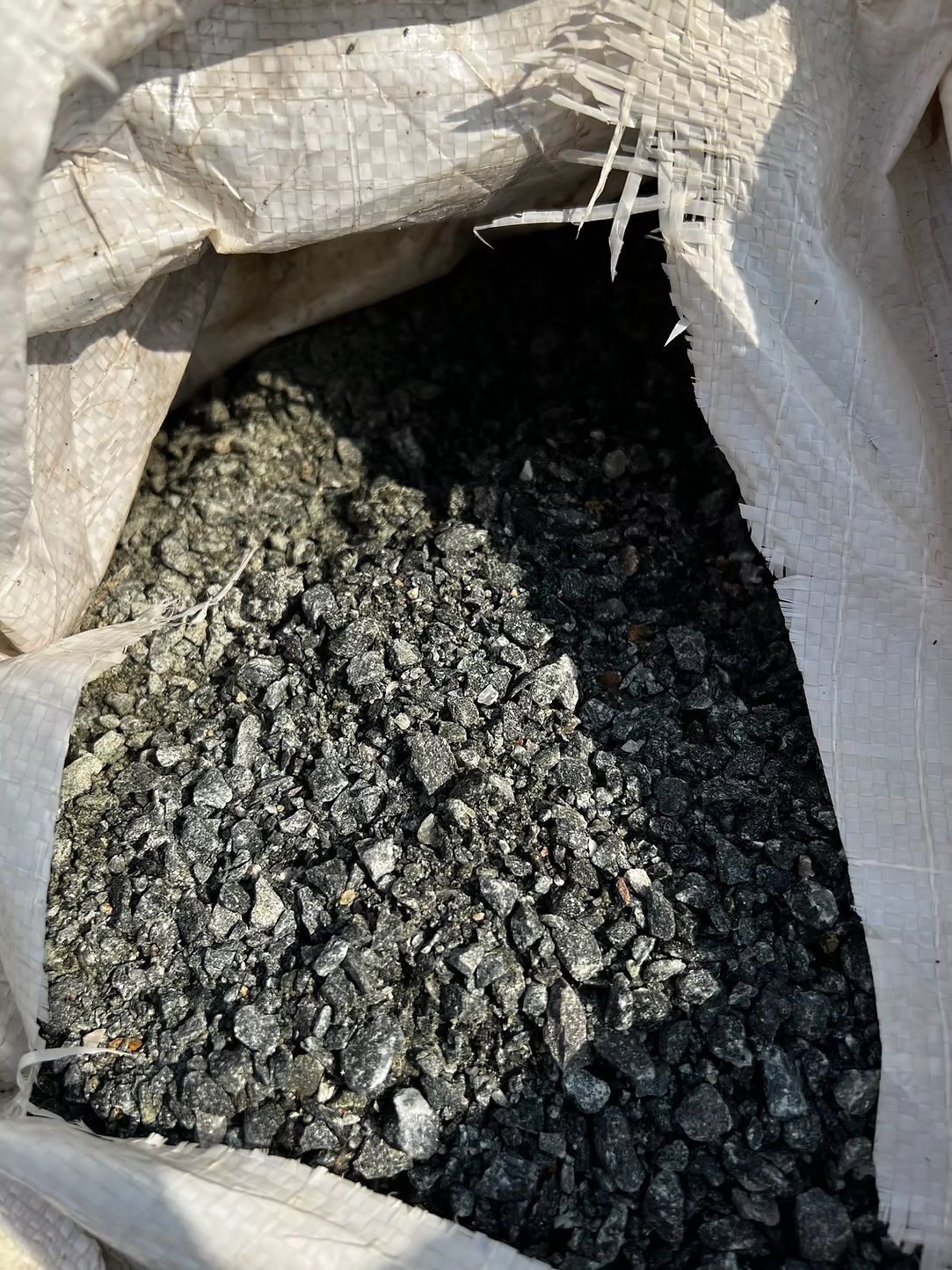 Bag of dark, granular material, likely coal or gravel, with bright light coming from above.