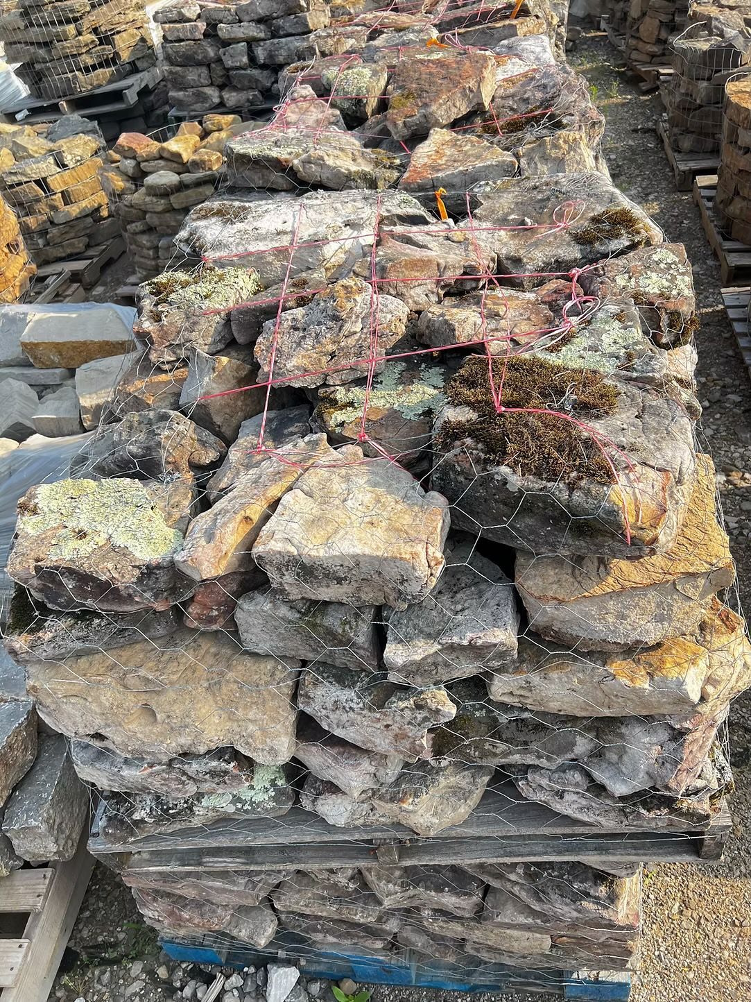 Stack of rough-cut, mossy grey and tan stones, possibly for landscaping.