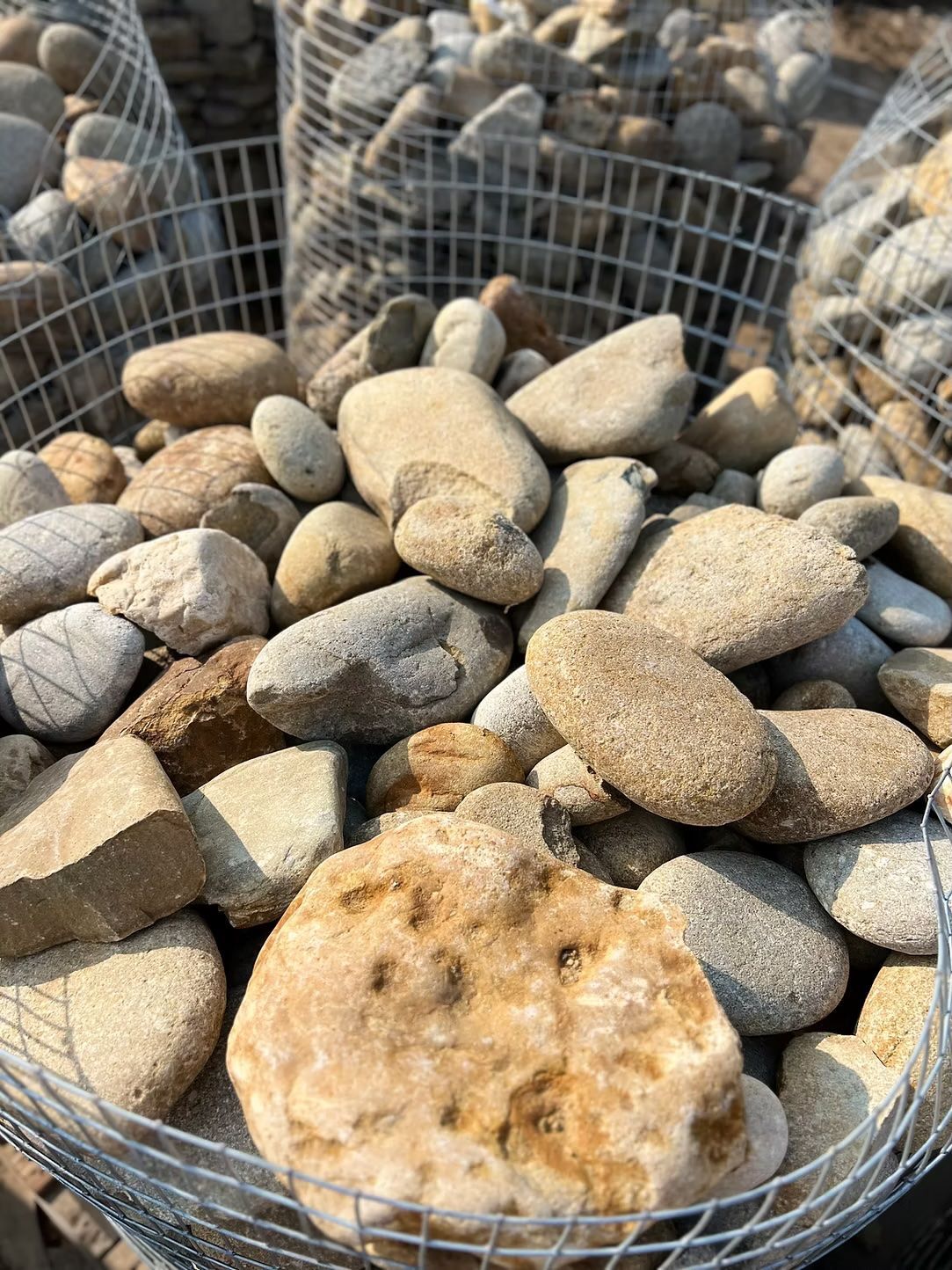 Rounded stones of various sizes and colors in a wire basket.