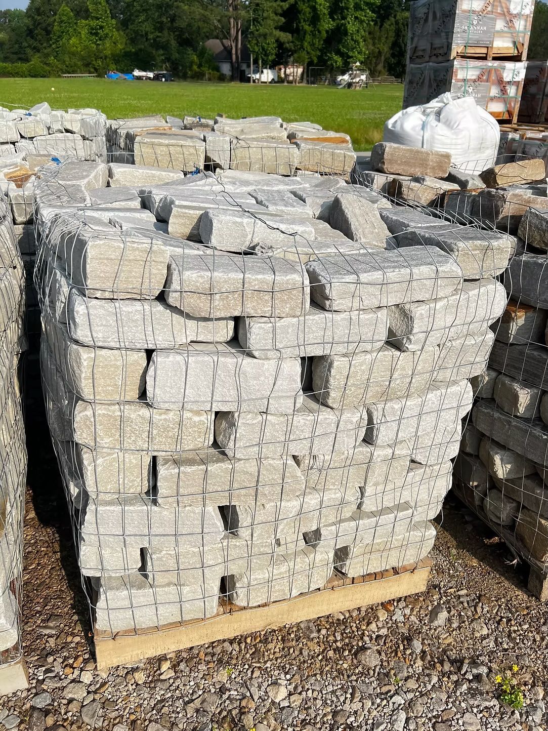 Pallet of gray stone blocks wrapped in wire, stacked outdoors.