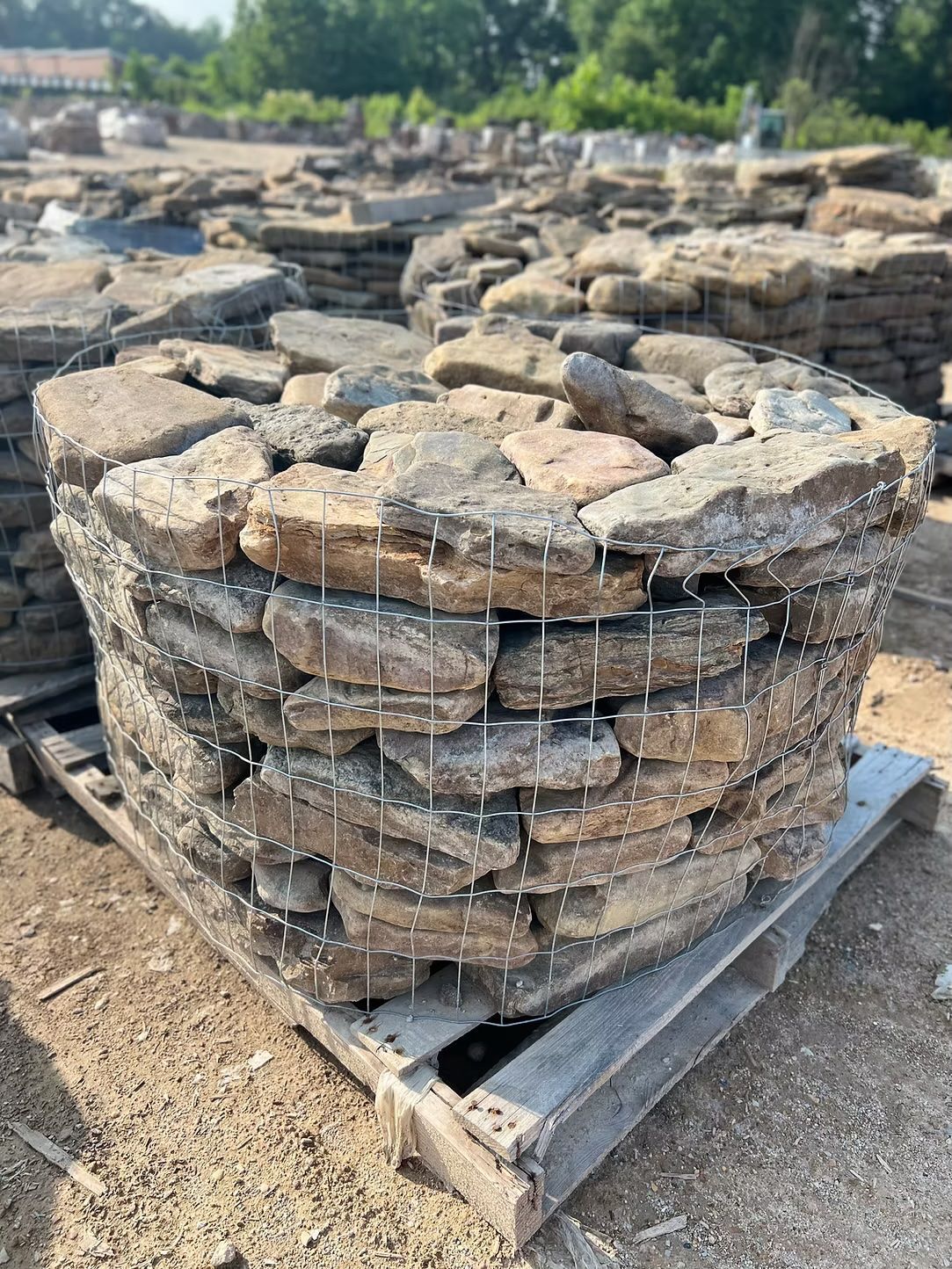 A circular pallet of stacked, irregularly shaped stones, held together by wire.