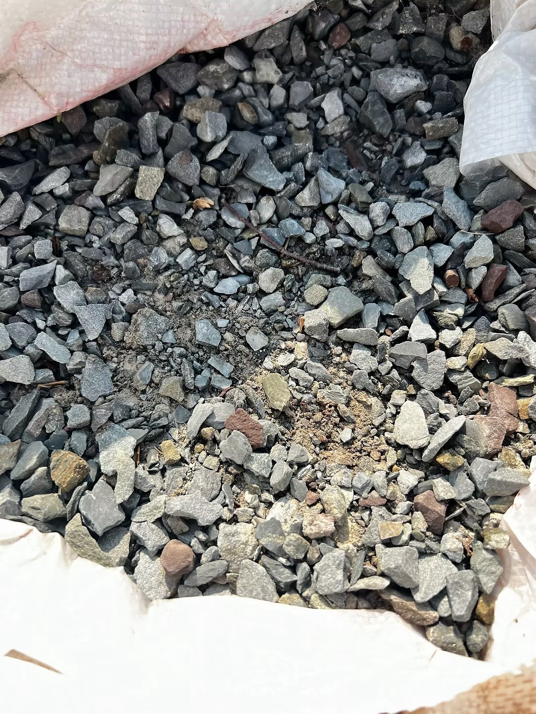Gravel in a white bag, varying shades of gray, small rocks.