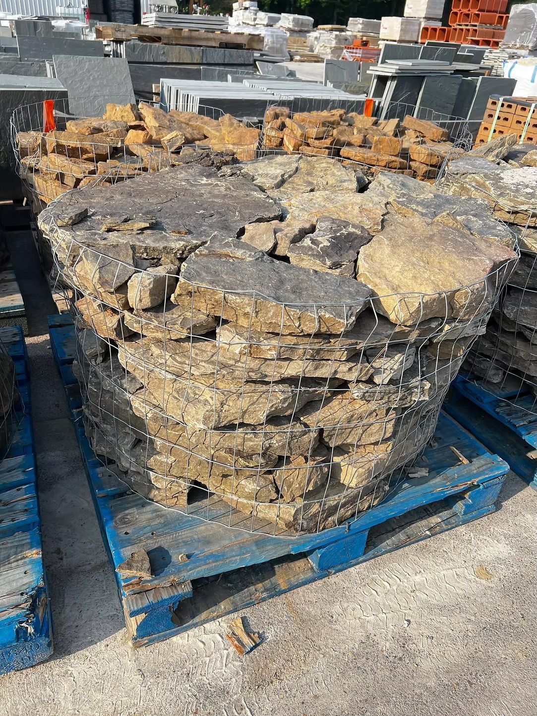 A stack of irregular, tan-colored stones on a blue wooden pallet.