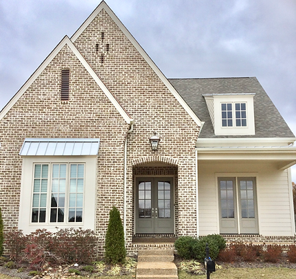 Brick house with a gray roof, green door, and light-colored trim.