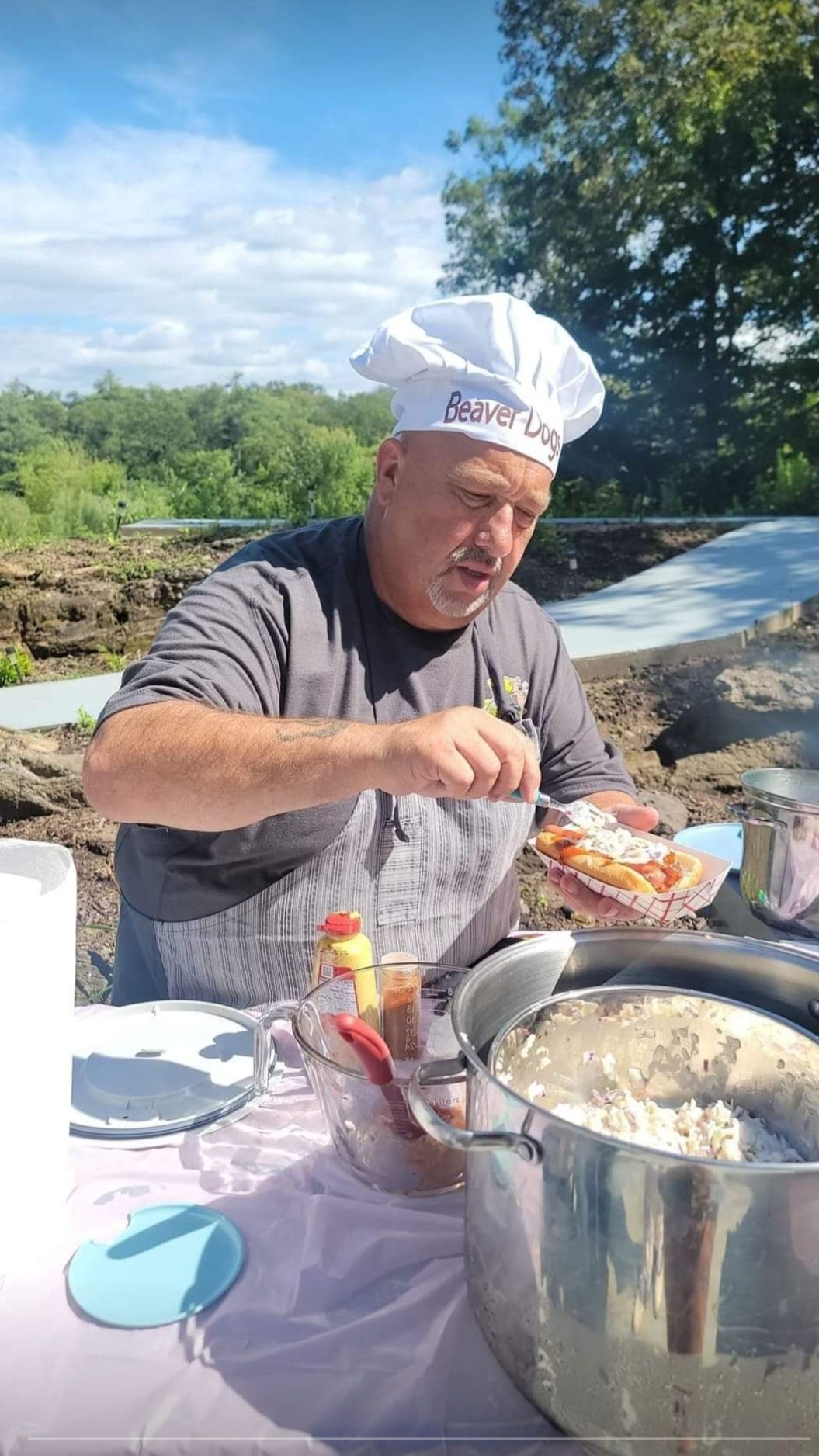 A man in a chef 's hat is preparing food on a table.