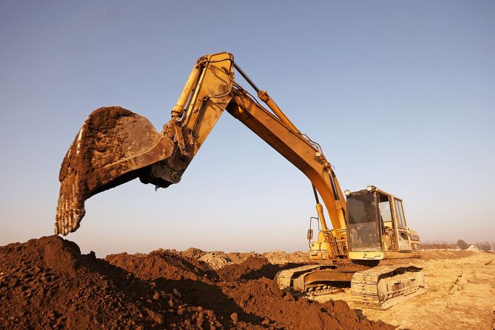 Backhoe loading dirt into dump truck on excavation site in Central Georgia