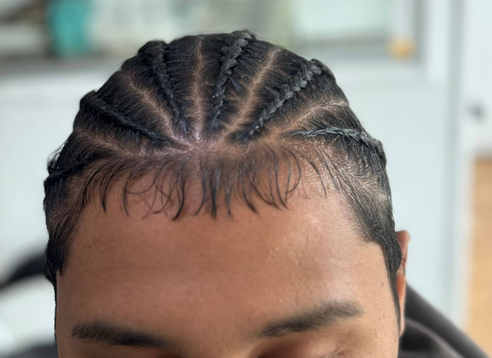 A close up of a man 's head with braids on it.