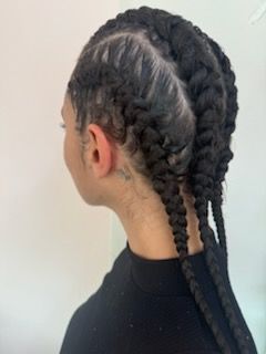 A woman with braids in her hair is wearing a black shirt.