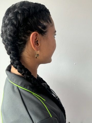 A woman is wearing a braided ponytail and earrings.