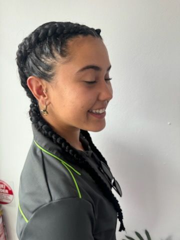 A woman with braids is smiling and wearing a gray jacket.