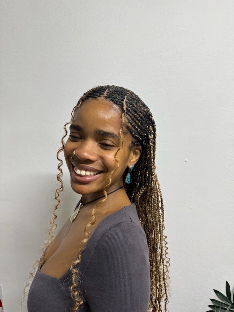 A woman with braids is smiling and wearing earrings.
