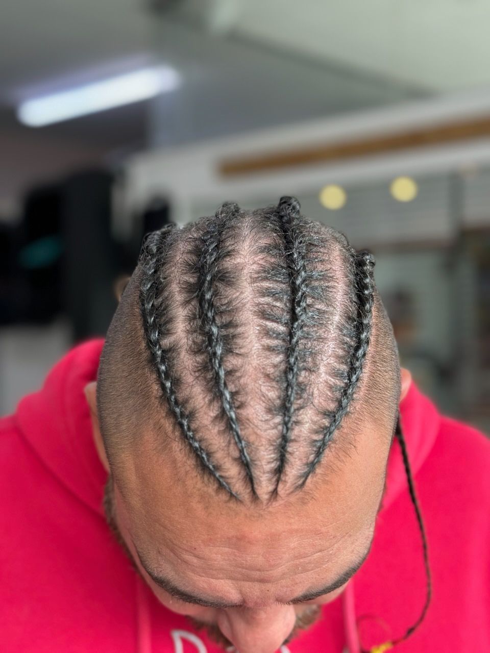 A man with braids in his hair is wearing a red hoodie.