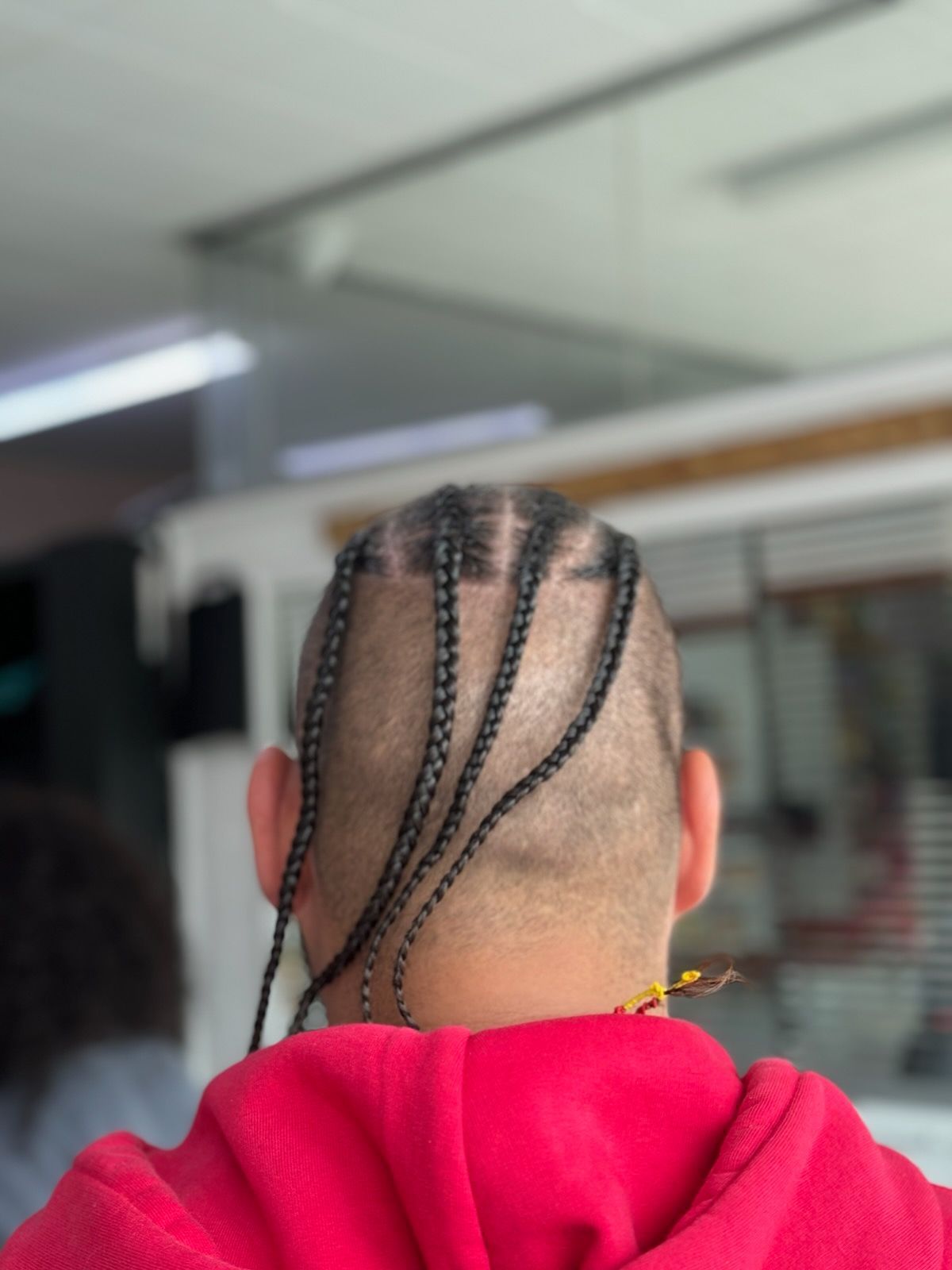 A man in a red hoodie has braids in his hair