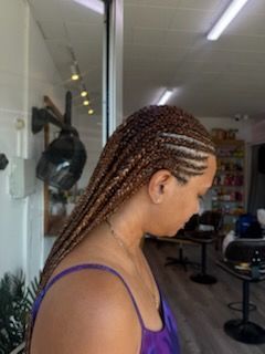 A woman with braids in her hair is standing in a salon.
