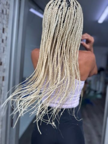 A woman with blonde braids is taking a picture of herself in a mirror.