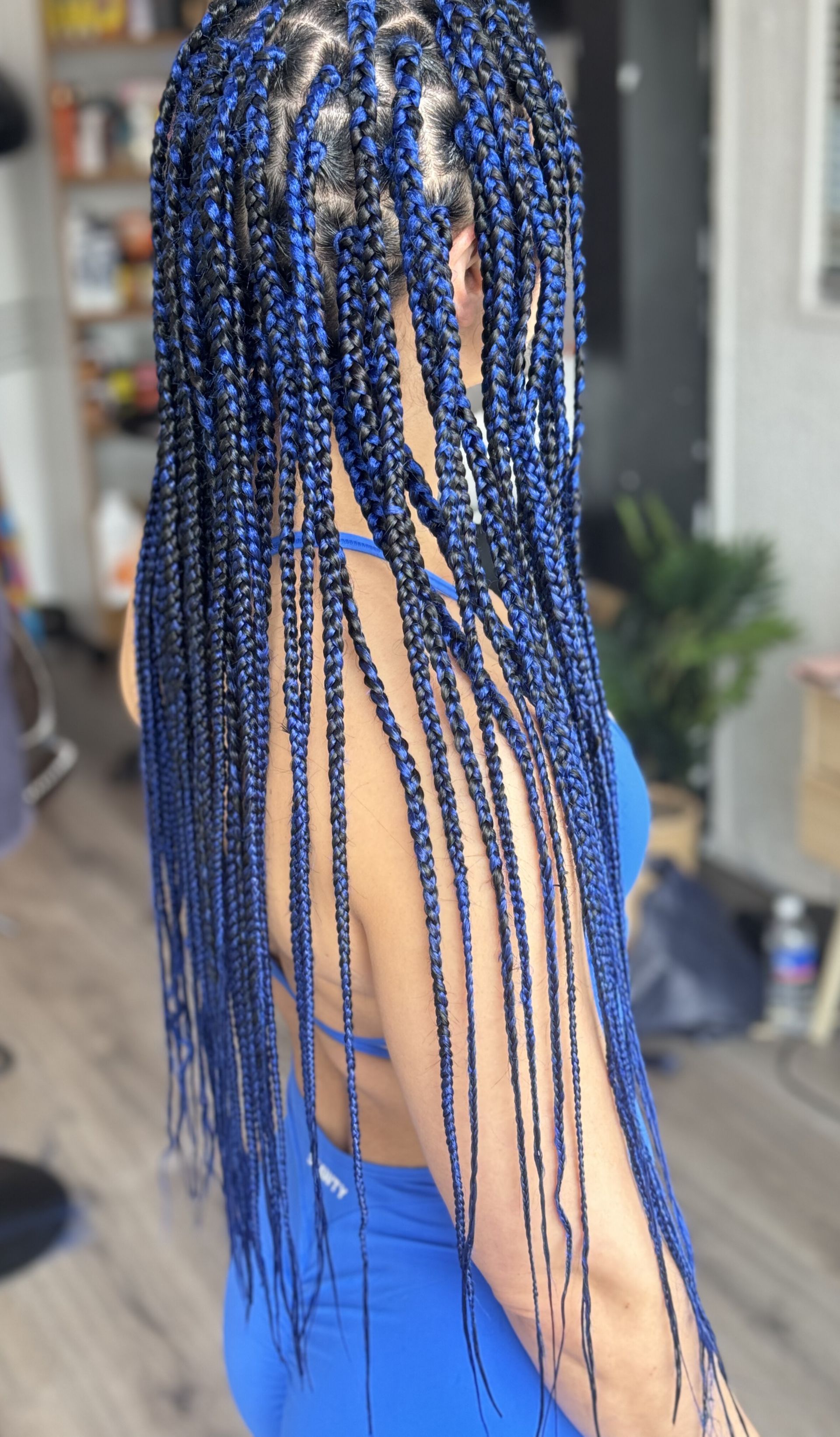 A woman with blue braids is wearing a blue dress.