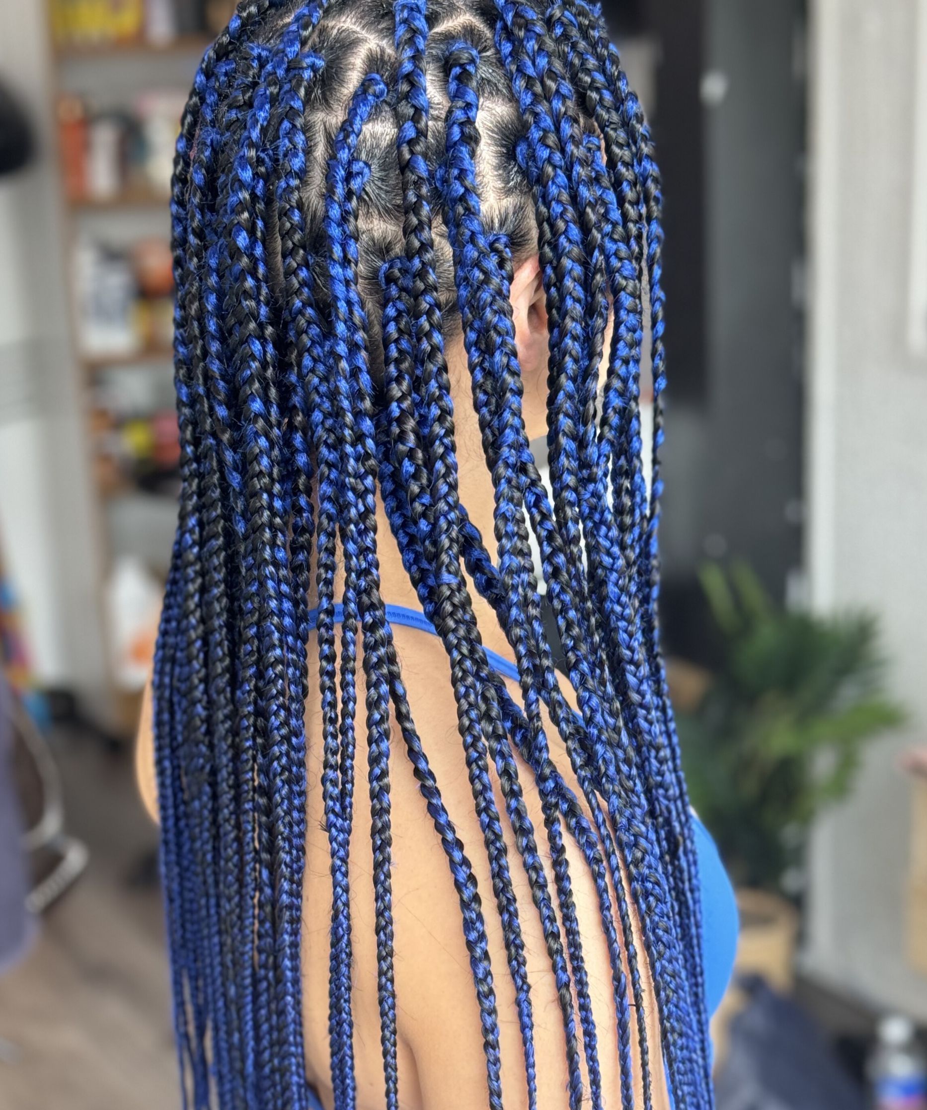 A woman with blue braids in her hair is standing in a room.