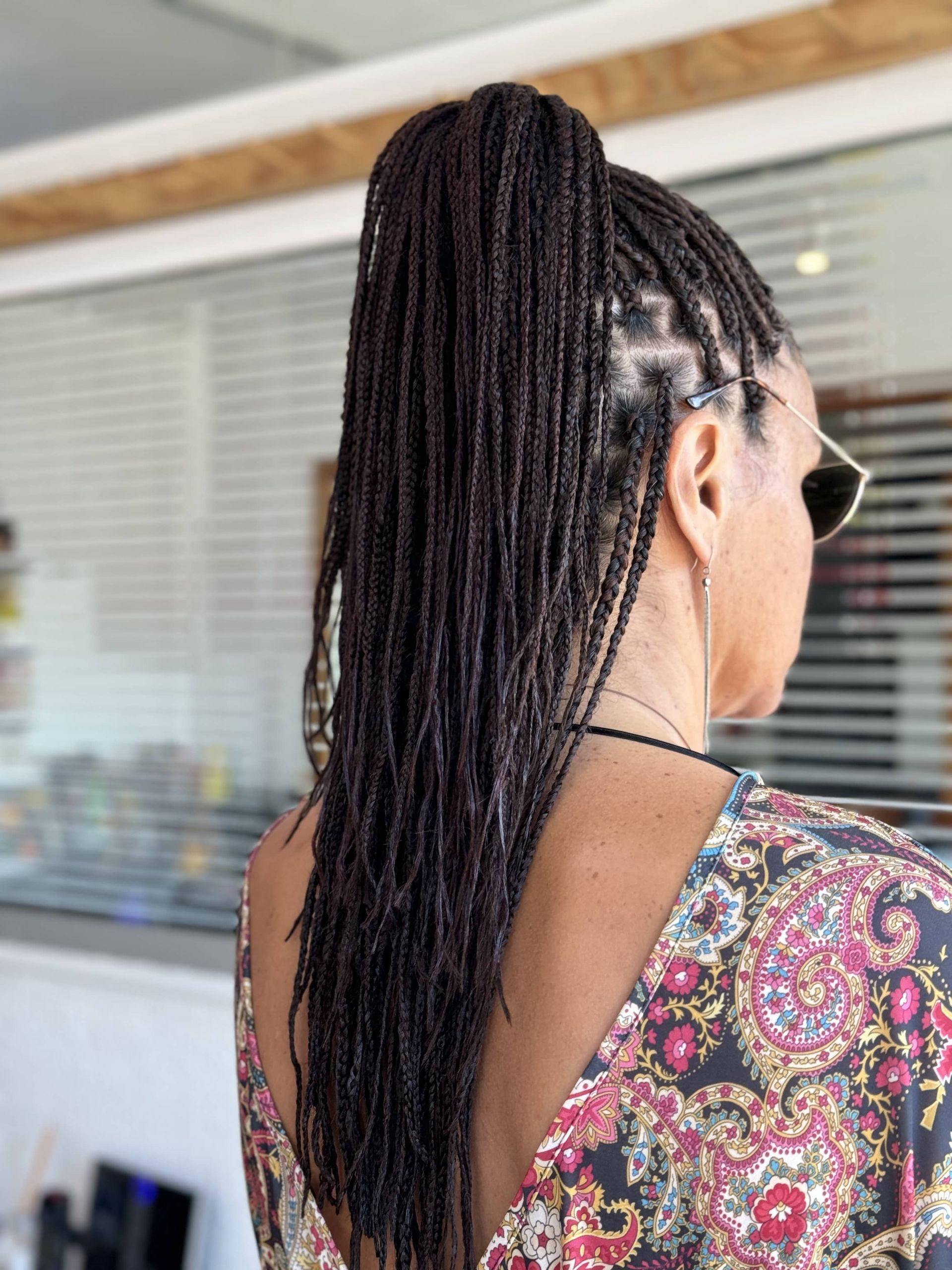A woman with braids in a ponytail is wearing sunglasses.