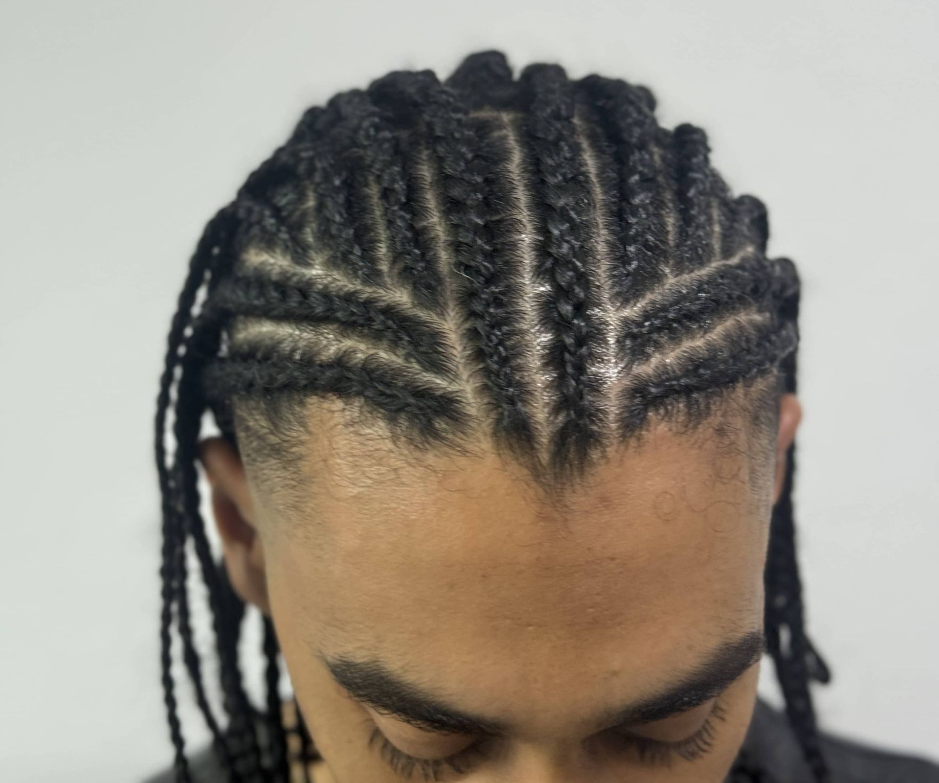 A close up of a man 's head with braids on it