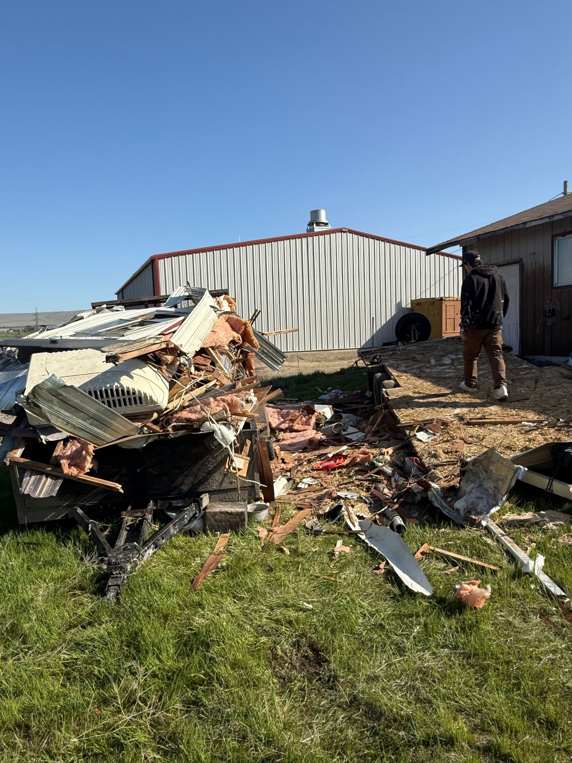 A man is standing in front of a pile of rubble in a field.