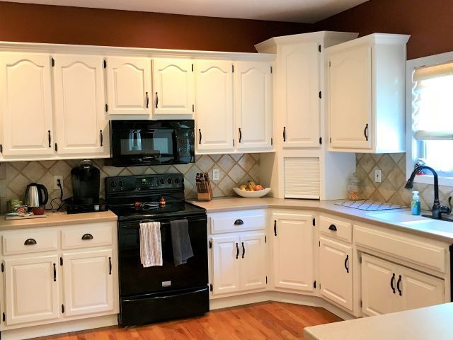 A kitchen with white cabinets and a black stove