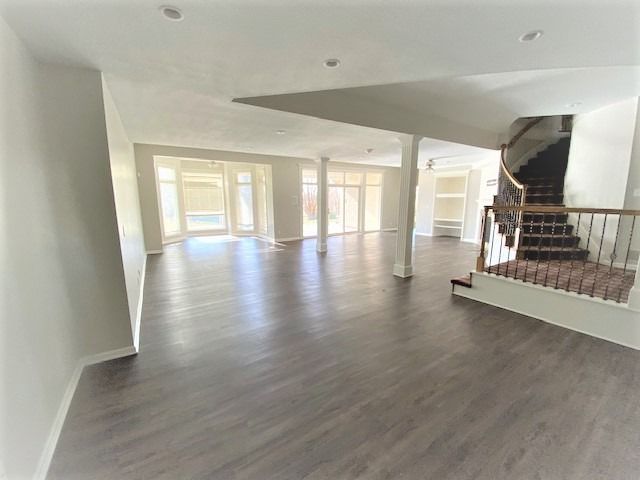 A large empty room with hardwood floors and stairs in a house.